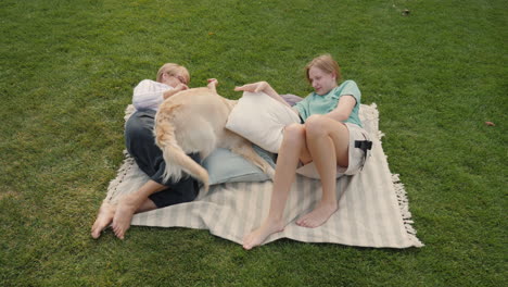 grandmother and granddaughter relaxing with dog on a picnic blanket