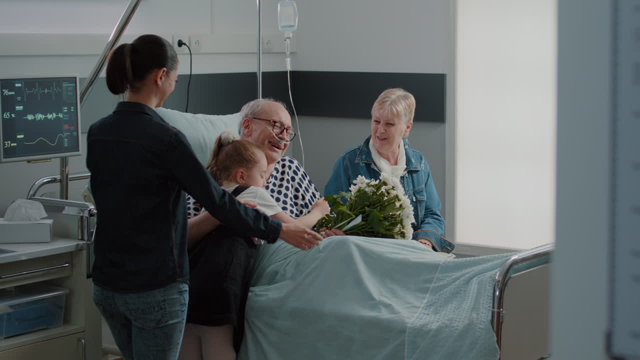 Aged patient with disease enjoying visit from little girl in hospital ward