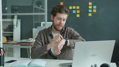 man checking smartwatch in office