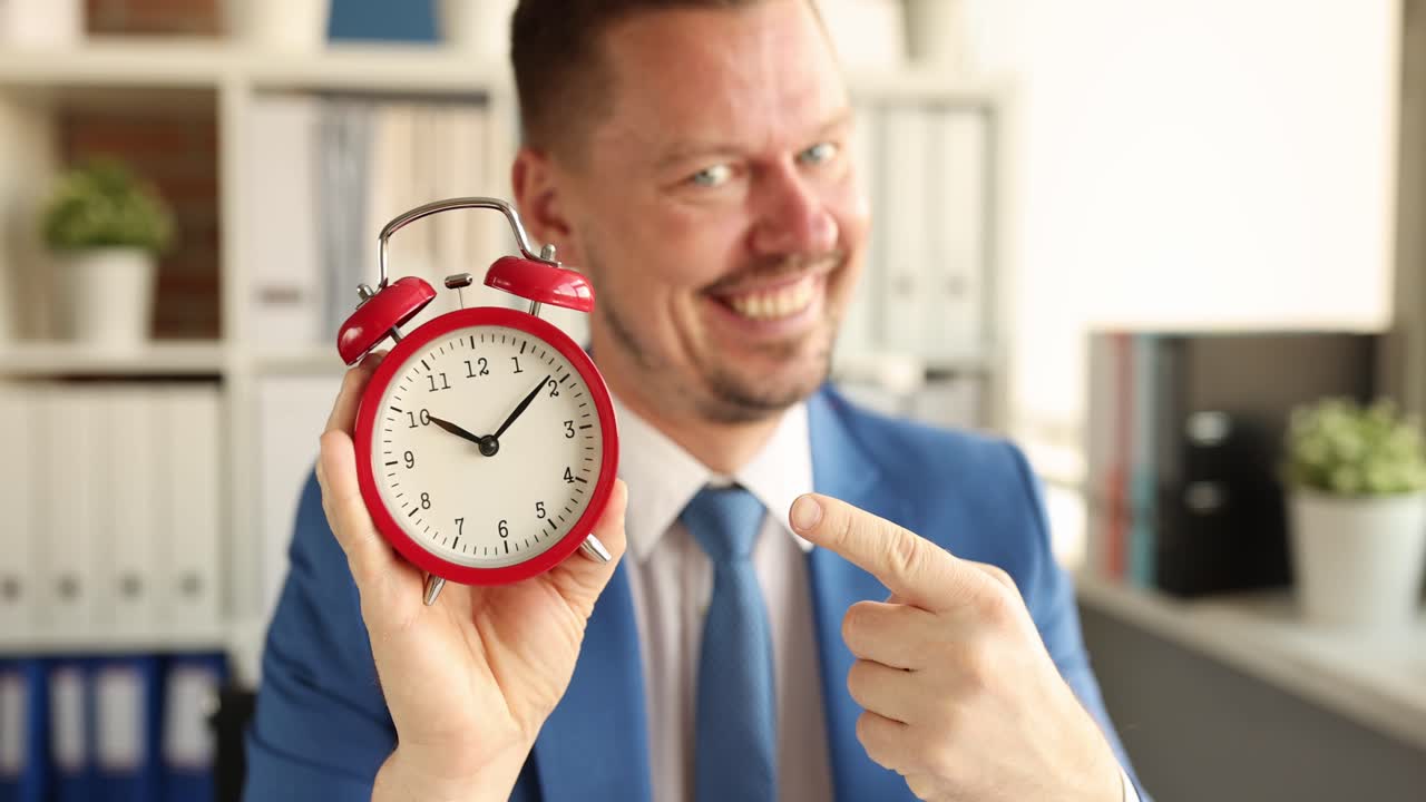 Happy professional man pointing finger at alarm clock