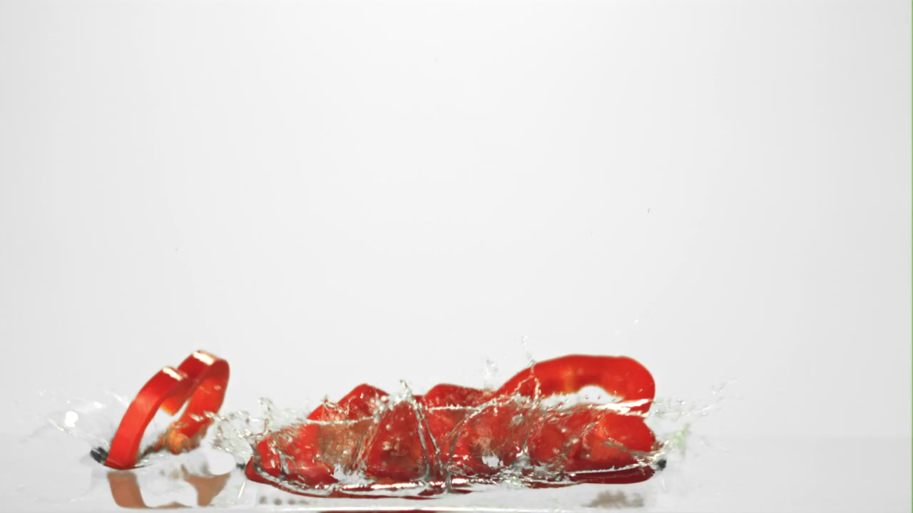 Red Bell Pepper Slices Falling into Water in Slow Motion