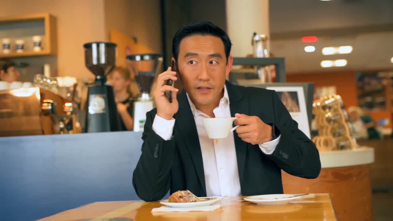 Businessman with coffee while talking on mobile phone 4k