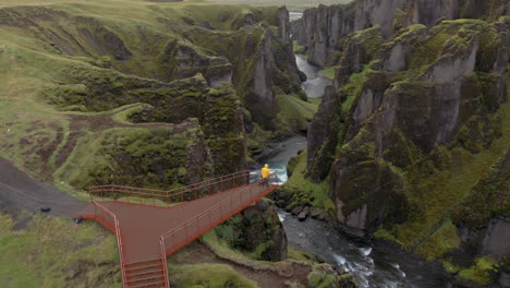 antena: volando junto a una persona con chaqueta amarilla de pie en la plataforma del cañón fjadrargljufur en islandia