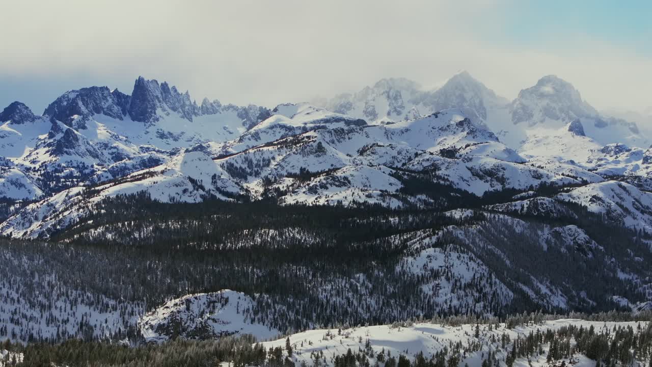 The Minarets jagged peaks mountain range summit vista Mammoth Mountain ski resort California winter spring deep snow Hemlocks Ritter Sierra Nevadas sunny blue sky clouds snowy deep snow forward pan up