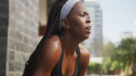 mujer afroamericana haciendo ejercicio al aire libre descansando respirando profundamente en la ciudad