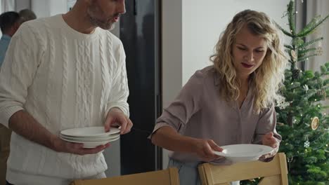 una feliz familia caucásica preparando la mesa para la víspera de navidad.