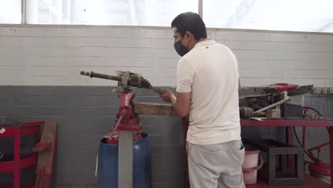 latin male mechanic repairing the drive shaft of a car at a workshop station garage at mexico latin-america