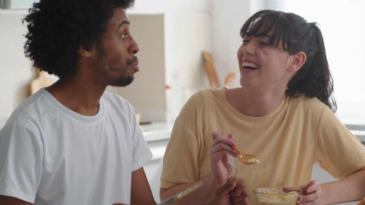 Young Woman Giving Spoon with Yogurt to Her Boyfriend during Breakfast
