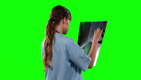 side view of female doctor looking at x-ray with green screen