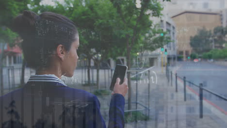 Animación-De-Múltiples-Gráficos-Sobre-La-Vista-Trasera-De-Una-Mujer-Birracial-Caminando-Y-Usando-Un-Teléfono-Inteligente