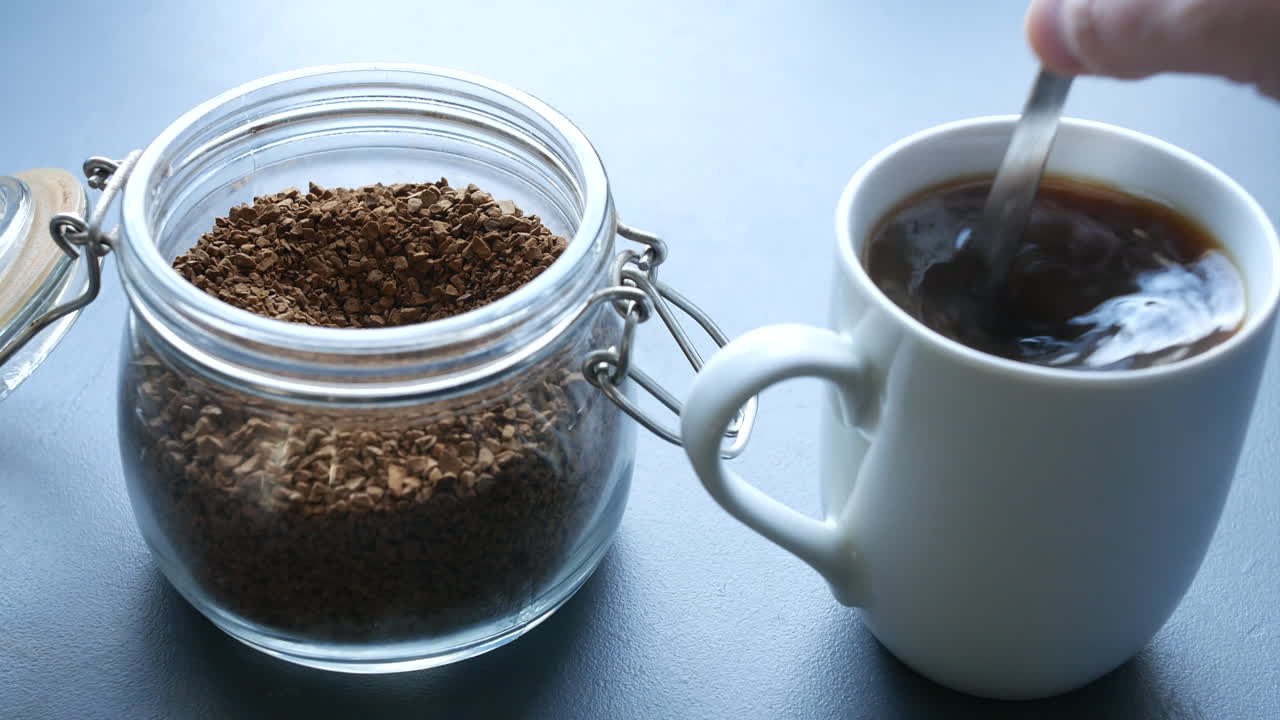 아침에 부엌에서 아침에 숟가락으로 김이 나는 뜨거운 커피를 휘젓다