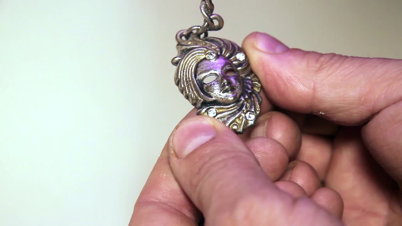 primer plano del llavero de recuerdo de máscara veneciana de metal en las manos