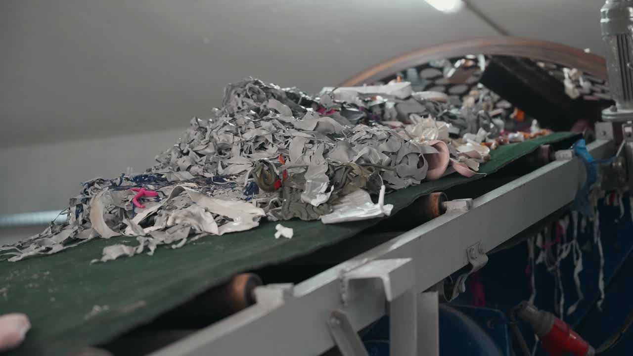 산업 재활용 작업 중 컨베이어로 운반되는 잘게 부서진 고무 조각