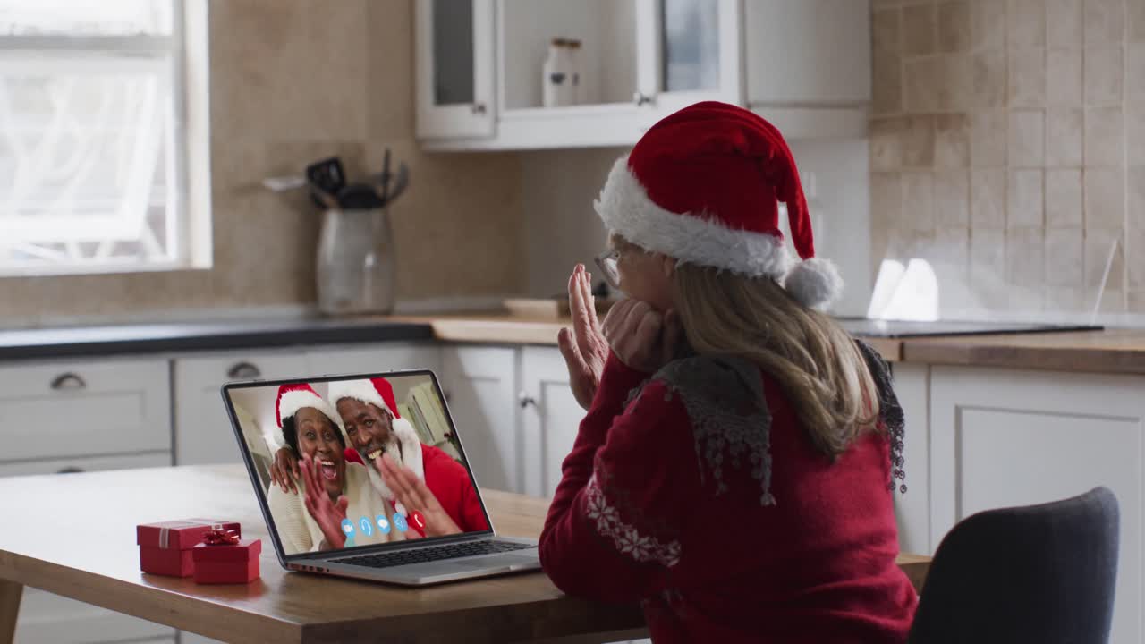 mujer caucásica con sombrero de papá noel en una videochat portátil durante la navidad en casa
