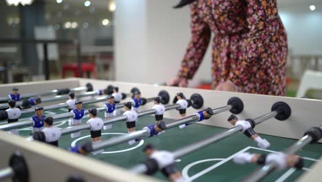 compañeros de trabajo anónimos jugando al futbolín durante el descanso