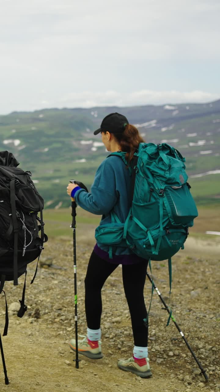 Donna con zaino e bastoncini da trekking che fa escursioni in un paesaggio montano