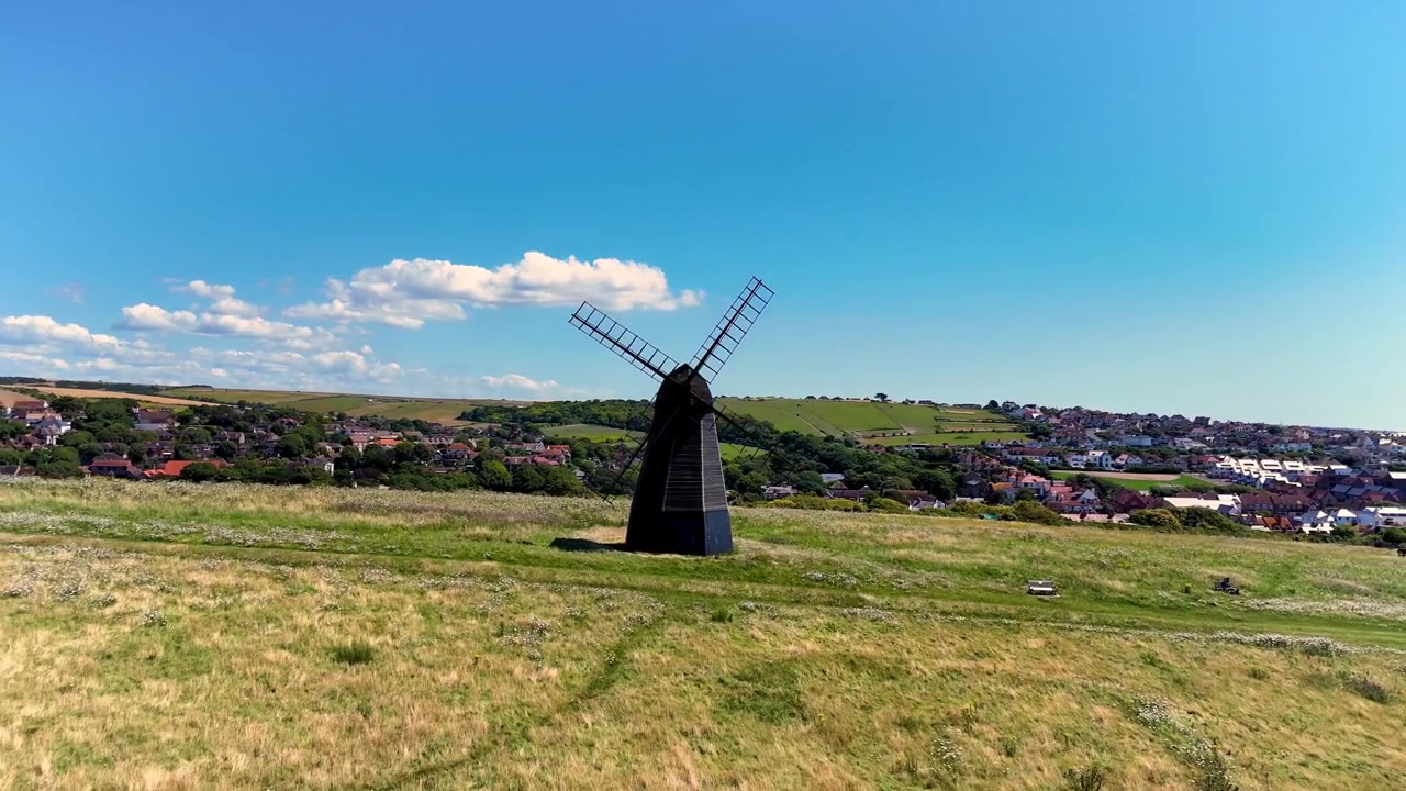 Rekaman drone 4K yang terbang menjauh dari kincir angin hitam indah di Rottingdean, Sussex.