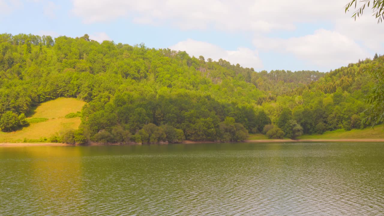 Peaceful lake in France with green hills and cloudy sky