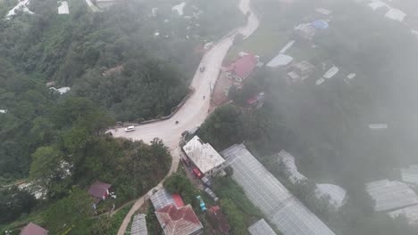 aerial view of a misty mountain road and rural landscape with greenhouses