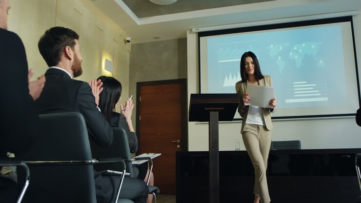 Caucasian female business speaker finishing her conference in a meeting and going away cheerfully while people clapping