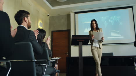 femme de race blanche conférencière d'affaires terminant sa conférence lors d'une réunion et s'en allant joyeusement pendant que les gens applaudissent