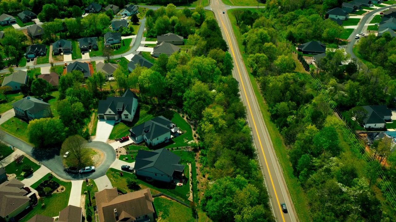 Ricco quartiere residenziale suburbano con un vicolo cieco, grandi case con piscine e un'autostrada vicina, che illustra il mercato immobiliare residenziale e lo sviluppo immobiliare.