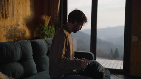 man packing a bag indoors with a mountain view