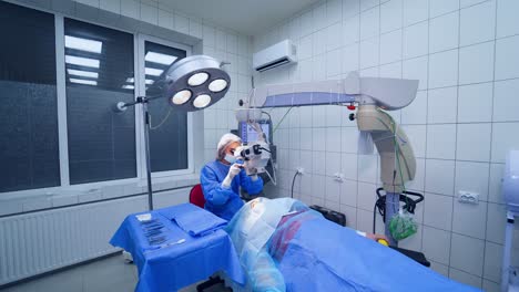 female ophthalmologist preparing the microscope for operation on eyes. doctor starts treating the patient's eyes in private clinic.