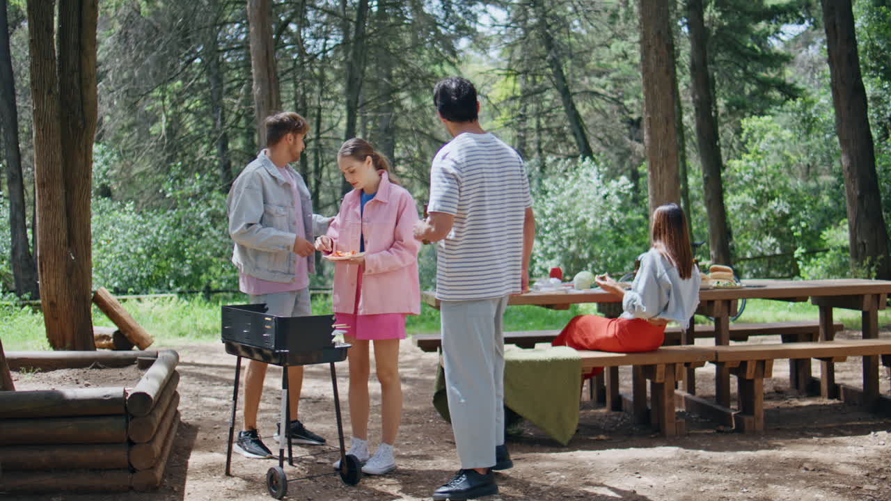 Group friends grilling food relaxing at forest picnic. Young people gathering