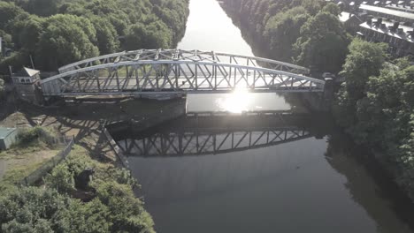 Aerial-pull-away-view-scenic-old-vintage-steel-archway-traffic-footbridge-over-Manchester-ship-canal-crossing