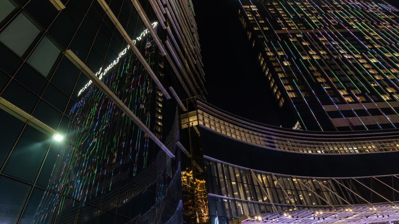 Arranha-céus modernos com luzes LED coloridas em constante mudança à noite.
