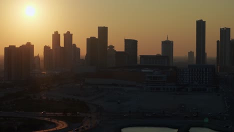 sanabis district, manama, bahrain. aerial view of highrise buildings backlit by setting sun