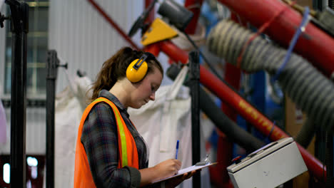 Side-view-of-young-caucasian-female-worker-checking-stocks-in-factory-4k