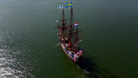 an aerial view of a 17th century wooden ship sailing out on greenport harbor on long island on a sunny day