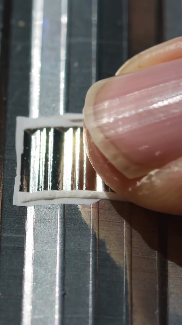 Finger entering frame pinching aligning and sliding white strip across ribbed metal on grooved base