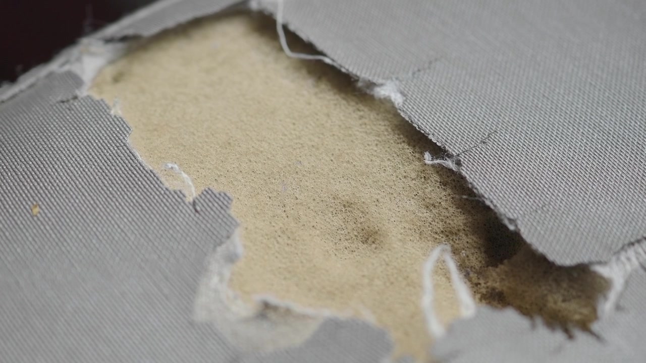 Close-up of Ripped Grey Fabric Revealing Foam Padding