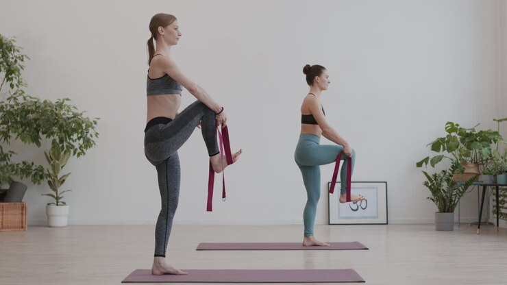 due giovani donne che usano cinture di yoga durante l'addestramento