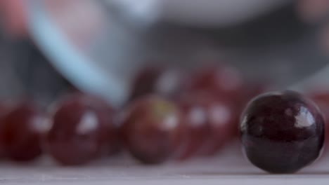 cerca de las uvas rojas vertidas en la tabla de cortar