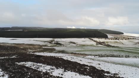 Snowy-rural-winter-valley-countryside-aerial-pan-right-slow-across-agricultural-farmland-landscape