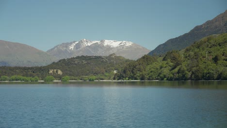 mujer rubia disfrutando de la vista panorámica del lago wakatipu con montañas en el fondo, enfoque superficial