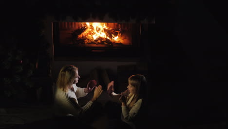 mom and daughter play by the fireplace in the evening a cozy warm house