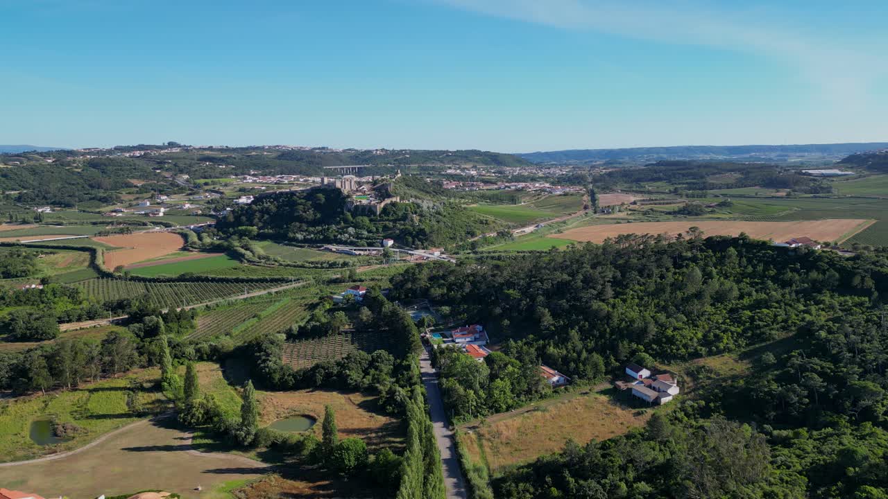Aerial view of rural Portugal with green fields, farms, and distant towns under a clear sky