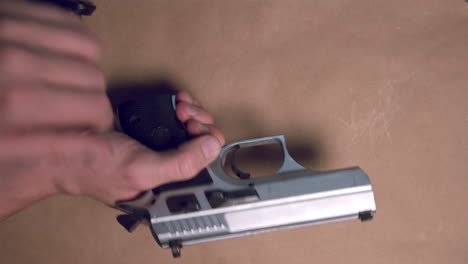 mano masculina sacando el arma de fuego de la mesa y descargando la revista con balas