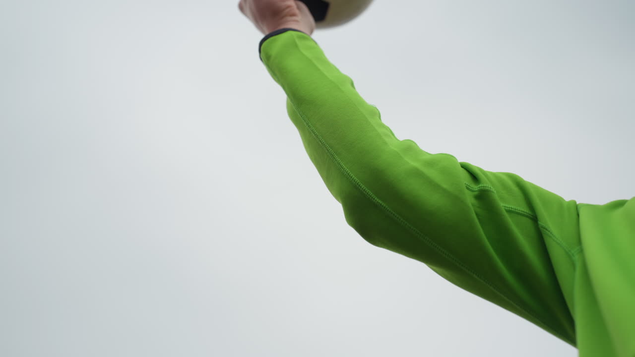 흐린 날씨 속에서 트레이너가 집중하며 활기찬 팔 들어 올리기를 지도하고, 운동선수는 강사의 면밀한 감독하에 흐린 날씨 속에서 역동적인 공 던지기 운동을 하고 있어요.