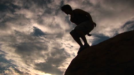 ángulo bajo de una silueta de excursionista en las montañas de santa bárbara saltando de roca en roca