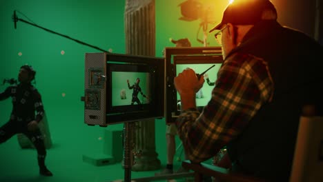 director looks at displays directs green screen cgi scene with actor wearing motion tracking suit and head rig. in the big film studio professional crew shooting blockbuster movie