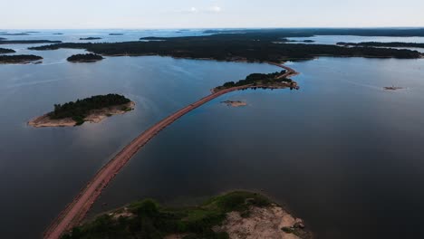 Vista-Aérea-Rodeando-Una-Carretera-Estrecha-Con-Un-Automóvil,-Uniendo-Islas-En-Aland,-Finlandia