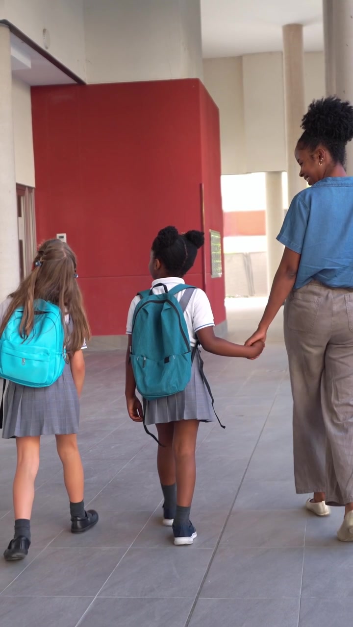 Teacher Walking with Two Young Schoolgirls Holding Hands