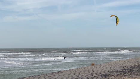 Weitwinkelaufnahme-Eines-Kitesurfers,-Der-An-Einem-Bewölkten-Tag-Auf-Großen-Wellen-Der-Nordsee-Rast