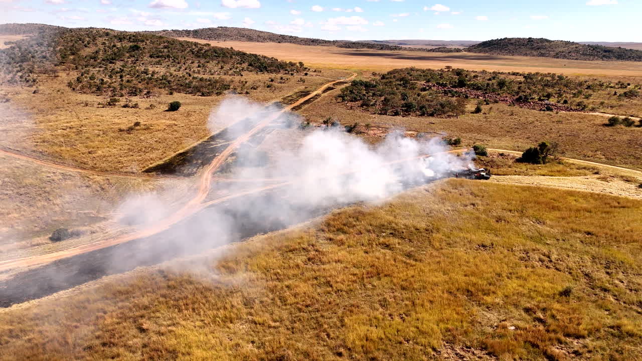 Smoke rises from planned fire line being burned in dry field of reserve, aerial